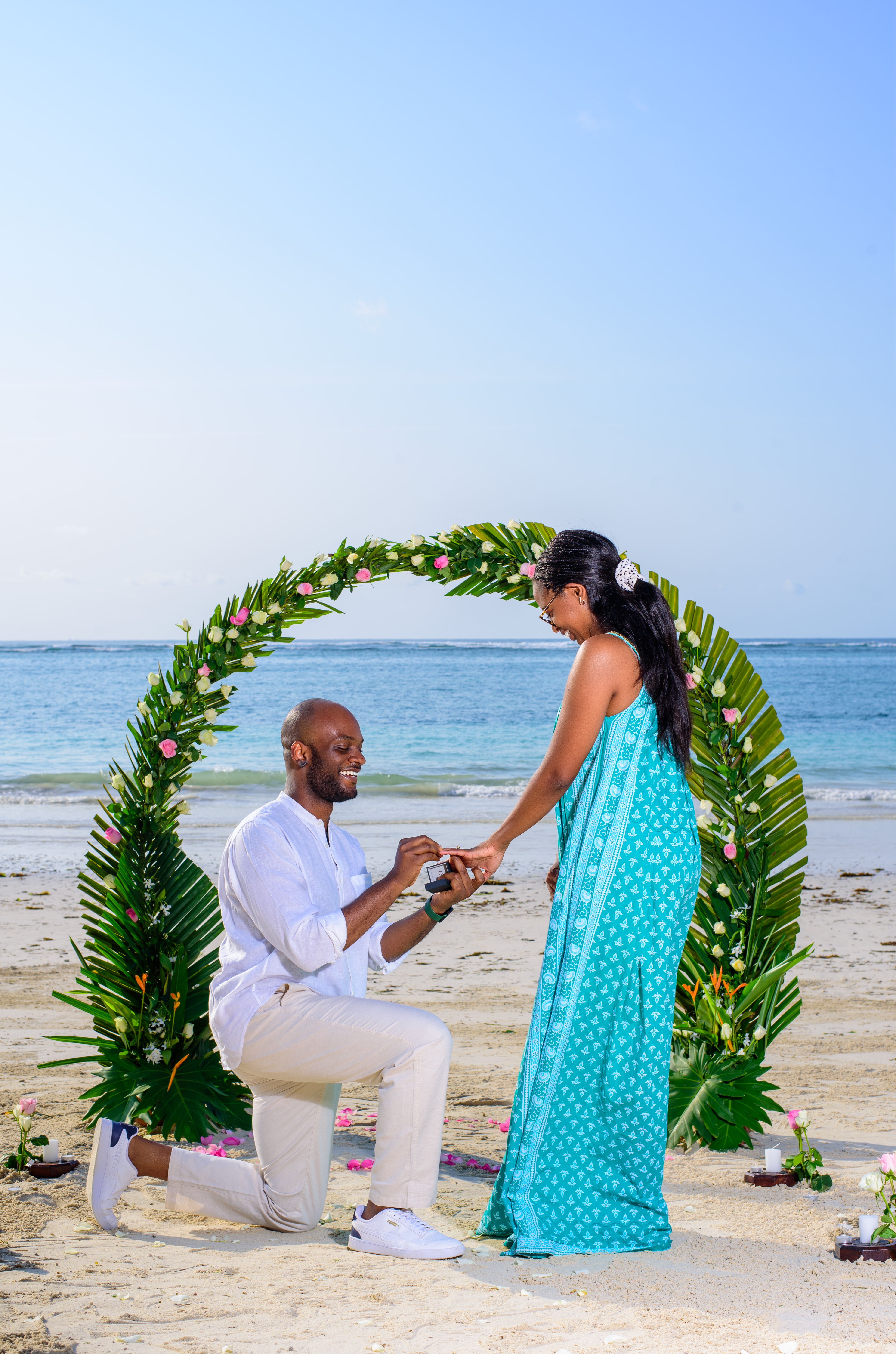 Beach proposal under a floral arch